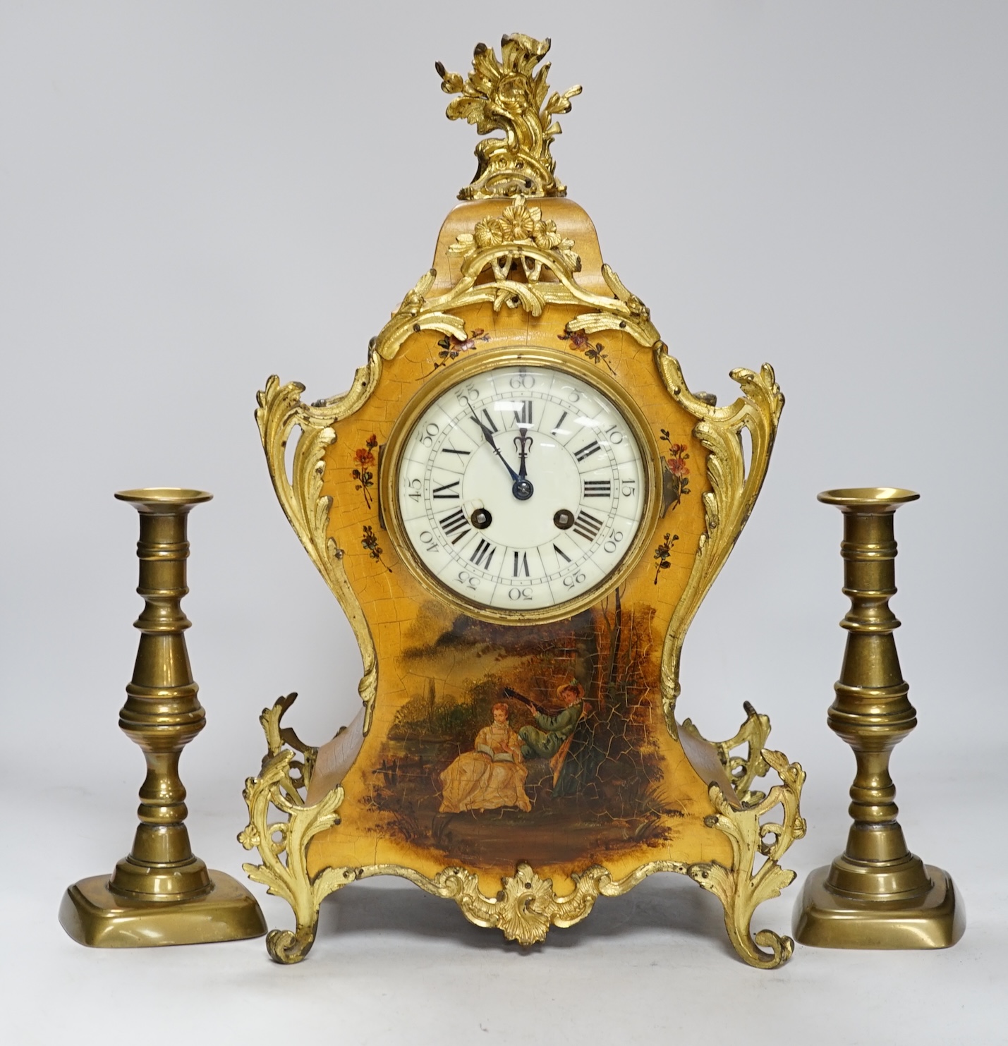 A late 19th century French Vernis Martin ormolu mounted clock with key and pendulum and a pair of brass candlesticks, tallest 44cm